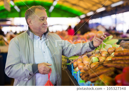 Middle aged man buying onions Middle aged man buying onions 105327348