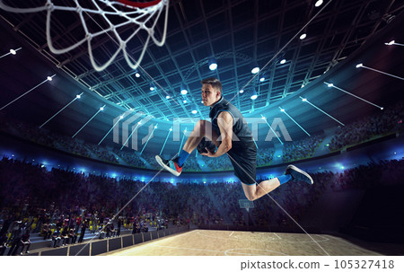 Slam dunk. Young man, professional basketball player on 3D stadium, arena during game, jumping with ball Slam dunk. Young man, professional basketball player on 3D stadium, arena during game, jumping with ball 105327418