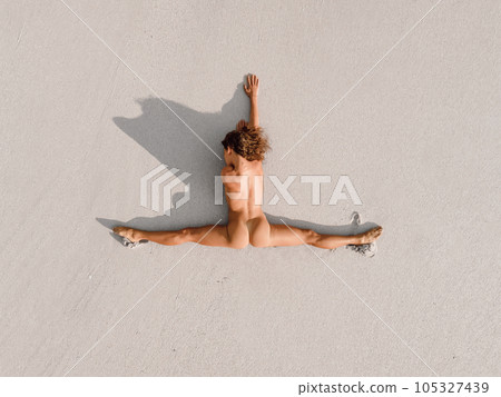 Aerial view of naked woman sunbathing on beach near the ocean. Woman with good stretch. 105327439
