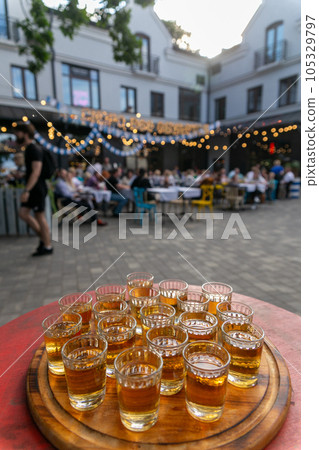 Small glasses filled with brandy on a wooden tray. 105329797
