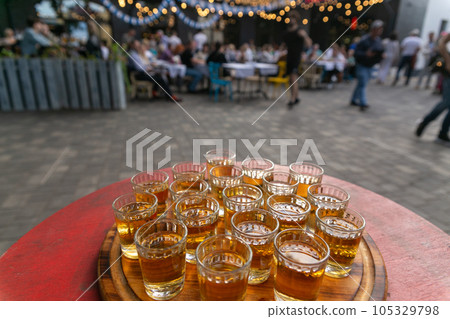 Small glasses filled with brandy on a wooden tray. 105329798