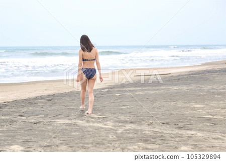 海灘上一位穿著圓點比基尼的年輕女子的後視圖 105329894