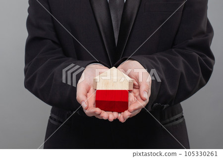 Polish person holding wooden house with flag of Poland Finance, investment, mortgage 105330261