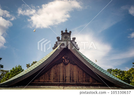 Summer at Umenomiya Taisha Shrine, the summer sky with gray herons flying and the roof of the worship hall 105330637