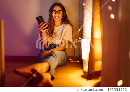 Woman in headphones before bedtime listening online to relaxing music. Remote work, internet concept 105331252