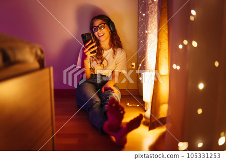 Woman in headphones before bedtime listening online to relaxing music. Remote work, internet concept 105331253