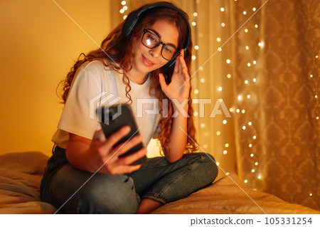 Woman in headphones before bedtime listening online to relaxing music. Remote work, internet concept 105331254