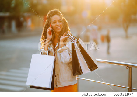 Young woman with shopping bags walking on street. Sale, shopping and happy people concept. 105331974