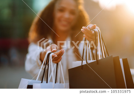 Young woman with shopping bags walking on street. Sale, shopping and happy people concept. 105331975