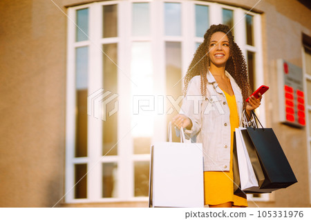 Young woman with shopping bags walking on street. Sale, shopping and happy people concept. 105331976