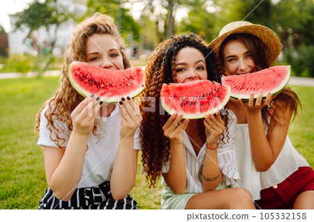 Three young woman have fun together and eating watermelon in hot summer day. Three young woman have fun together and eating watermelon in hot summer day. 105332158