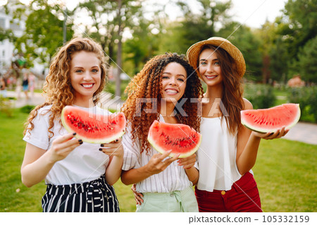 Three young woman have fun together and eating watermelon in hot summer day. Three young woman have fun together and eating watermelon in hot summer day. 105332159