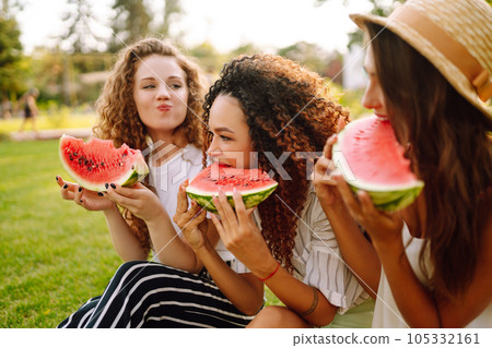 Three young woman have fun together and eating watermelon in hot summer day. Three young woman have fun together and eating watermelon in hot summer day. 105332161