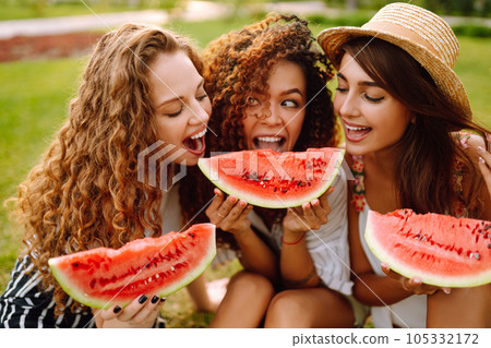 Cheerful happy friends camping on the grass, eating watermelon, laughing. Cheerful happy friends camping on the grass, eating watermelon, laughing. 105332172