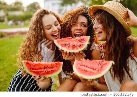 Three young woman have fun together and eating watermelon in hot summer day. Three young woman have fun together and eating watermelon in hot summer day. 105332173