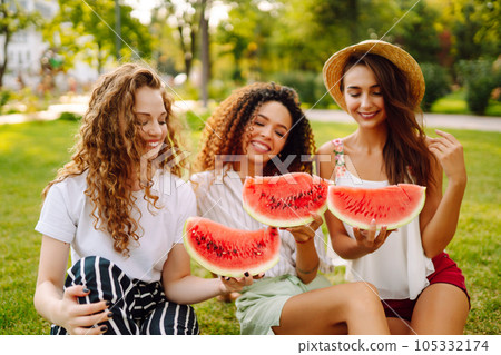 Cheerful happy friends camping on the grass, eating watermelon, laughing. Cheerful happy friends camping on the grass, eating watermelon, laughing. 105332174