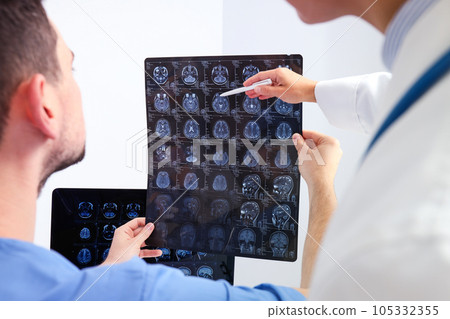 Doctors look at MRI images of a human head Doctors look at MRI images of a human head 105332355