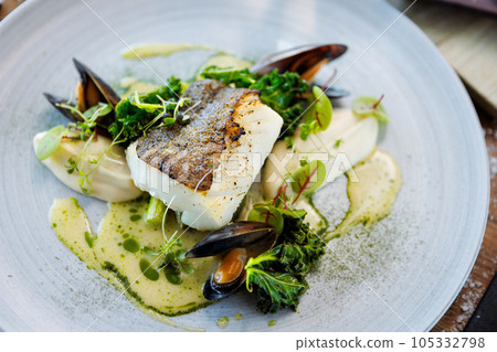 Cod fillet with cauliflower cream, asparagus, clam-wine sauce and mussles. Delicious seafood fish closeup served on a table for lunch in modern cuisine gourmet restaurant 105332798