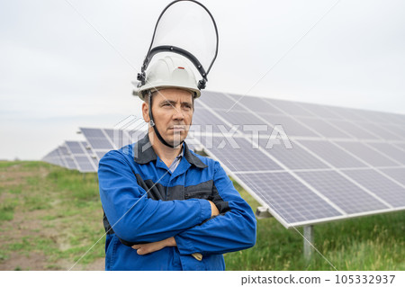 Service Engineer man standing with arms crossed in front of solar panels. Technician maintenance solar cells on Solar Energy Plant under morning sunlight. Technology solar energy renewable 105332937