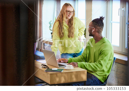 Smiling young man and woman working together on project online, remotely. Cooperation and discussion. Using laptop Smiling young man and woman working together on project online, remotely. Cooperation and discussion. Using laptop 105333153