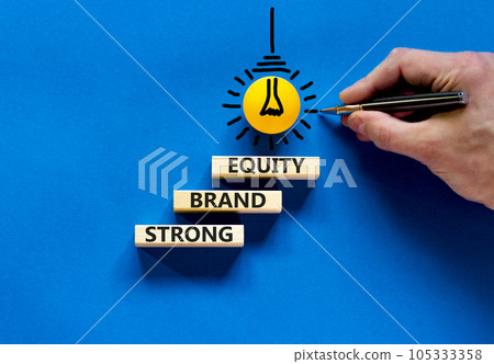 Strong brand equity symbol. Concept words Strong brand equity on wooden blocks on a beautiful blue table blue background. Businessman hand. Business, finacial and strong brand equity concept. 105333358