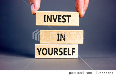 Invest in yourself symbol. Concept words Invest in yourself on wooden block on a beautiful grey table grey background. Businessman hand. Business and Invest in yourself concept. Copy space. 105333363