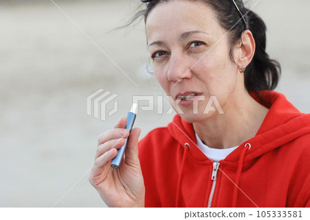 Electronic cigarette technology. Adult woman smokes hybrid cigarette device with real tobacco refills and heating pad, tobacco heating system. Technology between analog and electronic cigarettes 105333581