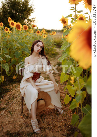 Woman in a dress in a field of sunflowers on a chair Woman in a dress in a field of sunflowers on a chair 105333747