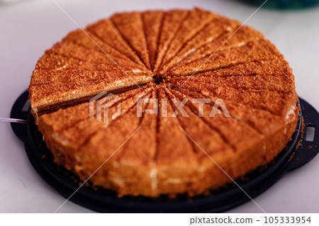 Photo of a honey cake in a cafe. A modern cake with a cut pieces on white background, cake stand. candy bar. selective focus. Photo of a honey cake in a cafe. A modern cake with a cut pieces on white background, cake stand. candy bar. selective focus. 105333954