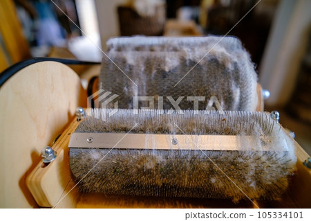 Wool felting. The step of combing the material in a special carding machine. Focus on foreground Wool felting. The step of combing the material in a special carding machine. Focus on foreground 105334101