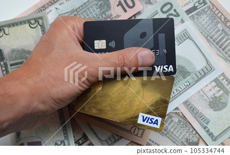 Visa bank card in a man's hand against the background of us dollars Visa bank card in a man's hand against the background of us dollars 105334744