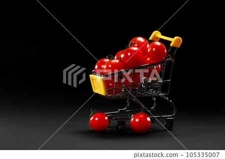 Mini shopping cart with cherry tomatoes on black background. Healthy eating and vegetarian food, cooking concept. selective focus. copy space. Mini shopping cart with cherry tomatoes on black background. Healthy eating and vegetarian food, cooking concept. selective focus. copy space. 105335007
