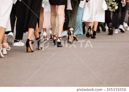 the feet of the group of people are walking outdoors. graduation day. stylish young guys and girls in stylish shoes. the feet of the group of people are walking outdoors. graduation day. stylish young guys and girls in stylish shoes. 105335058