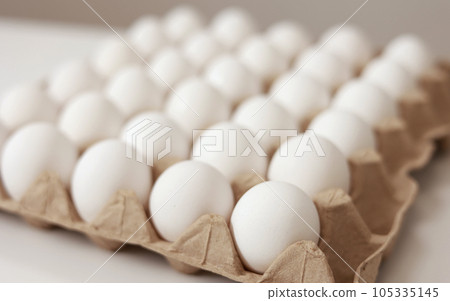 Close Up of raw chicken eggs in paper egg tray on white background. Group of Fresh white Eggs in a cardboard cassette. Organic food from nature good for health. Close Up of raw chicken eggs in paper egg tray on white background. Group of Fresh white Eggs in a cardboard cassette. Organic food from nature good for health. 105335145