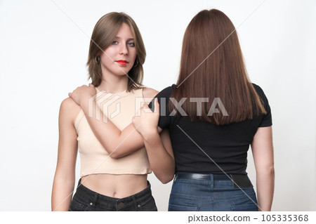 Two generations, teenager daughter and adult mother hugging each other. Caucasian ethnicity daughter stands facing and looking at camera, mom standing with her back. Studio shot, part of photo series Two generations, teenager daughter and adult mother hugging each other. Caucasian ethnicity daughter stands facing and looking at camera, mom standing with her back. Studio shot, part of photo series 105335368