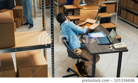 Female entrepreneur analyzing products from warehouse racks, looking at merchandise and boxes before shipping goods order. Young woman working in storage room with supply chain. Tripod shot. Female entrepreneur analyzing products from warehouse racks, looking at merchandise and boxes before shipping goods order. Young woman working in storage room with supply chain. Tripod shot. 105336686