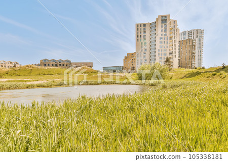 some tall buildings in the distance, with green grass growing on the ground and blue sky above them all around some tall buildings in the distance, with green grass growing on the ground and blue sky above them all around 105338181