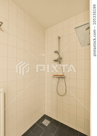 a bathroom with tiled walls and black tile flooring on the shower wall, there is a toilet in the corner 105338199