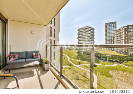 a balcony with chairs and couches on the outside, looking out onto some buildings in the distance to the right a balcony with chairs and couches on the outside, looking out onto some buildings in the distance to the right 105338213