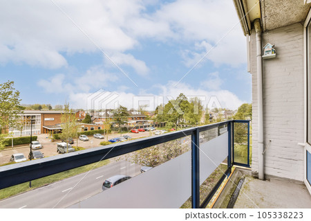 a balcony with cars parked on the street and houses in the background, taken from an apartment window looking out 105338223