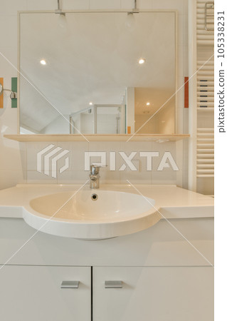 a white bathroom with a sink and mirror in the corner on the wall above it is a towel rack that has been used for 105338231