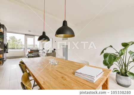 a dining room with a wooden table and two lamps hanging from the ceiling over it is an open living area a dining room with a wooden table and two lamps hanging from the ceiling over it is an open living area 105338280