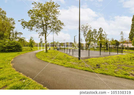 a park with some trees and a tennis court in the middle part of the park, on a sunny day 105338319