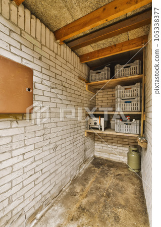 the inside of a building with some boxes on the wall and shelves in the corner to the right, there is an open door 105338377