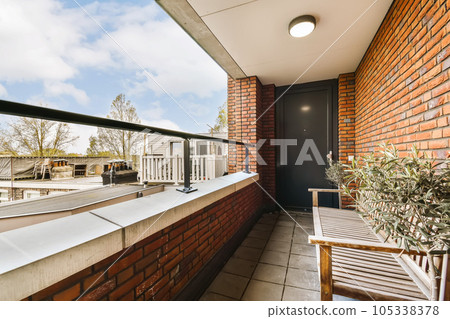 a balcony with some plants on the side and a blue sky in the top right hand corner is an open door 105338378
