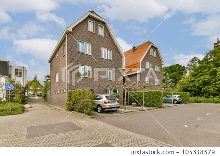 a street in the netherlands with houses and cars parked on both sides, there is a blue sky above them a street in the netherlands with houses and cars parked on both sides, there is a blue sky above them 105338379