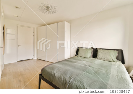 a bedroom with a bed and closets on the wall behind it, there is a green comforter in front of the bed 105338457