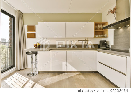 a modern kitchen with wood flooring and white cabinetry, in the daytime light shining on the window pane a modern kitchen with wood flooring and white cabinetry, in the daytime light shining on the window pane 105338484