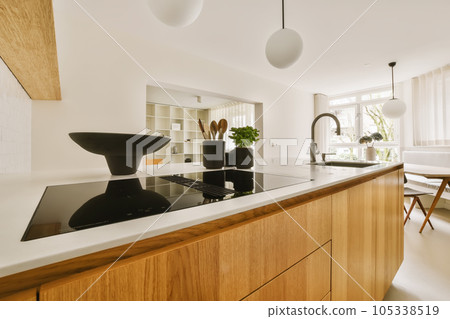 a modern kitchen with wood cabinets and white countertops in the center of the room is a large black bowl on the island a modern kitchen with wood cabinets and white countertops in the center of the room is a large black bowl on the island 105338519