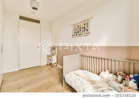 a child's room with white walls and wood flooring, including a cribt bed in the corner a child's room with white walls and wood flooring, including a cribt bed in the corner 105338520